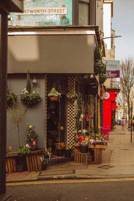 A florist shop on Harlington High Street displaying a vibrant floral arrangement outside; the arrangement includes a variety of fresh flowers such as pink roses, white lilies, and purple irises, arran